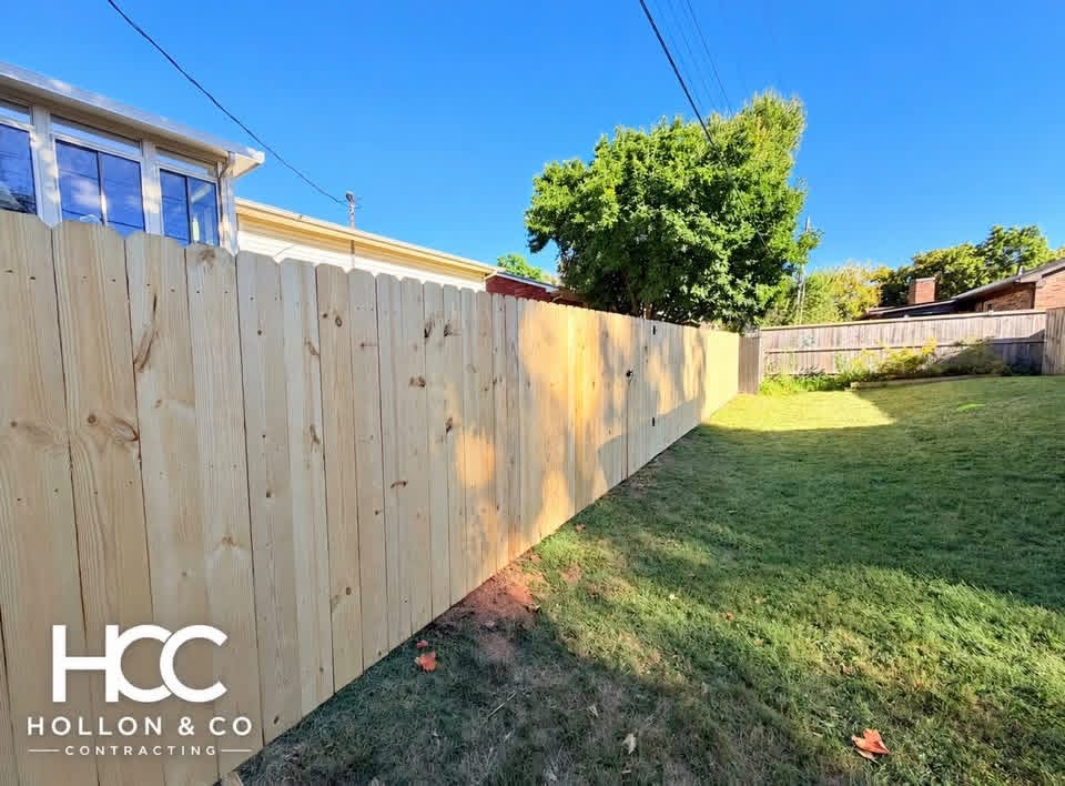 Wooden privacy fence along the side of a lawn, with the Hollon and Co logo